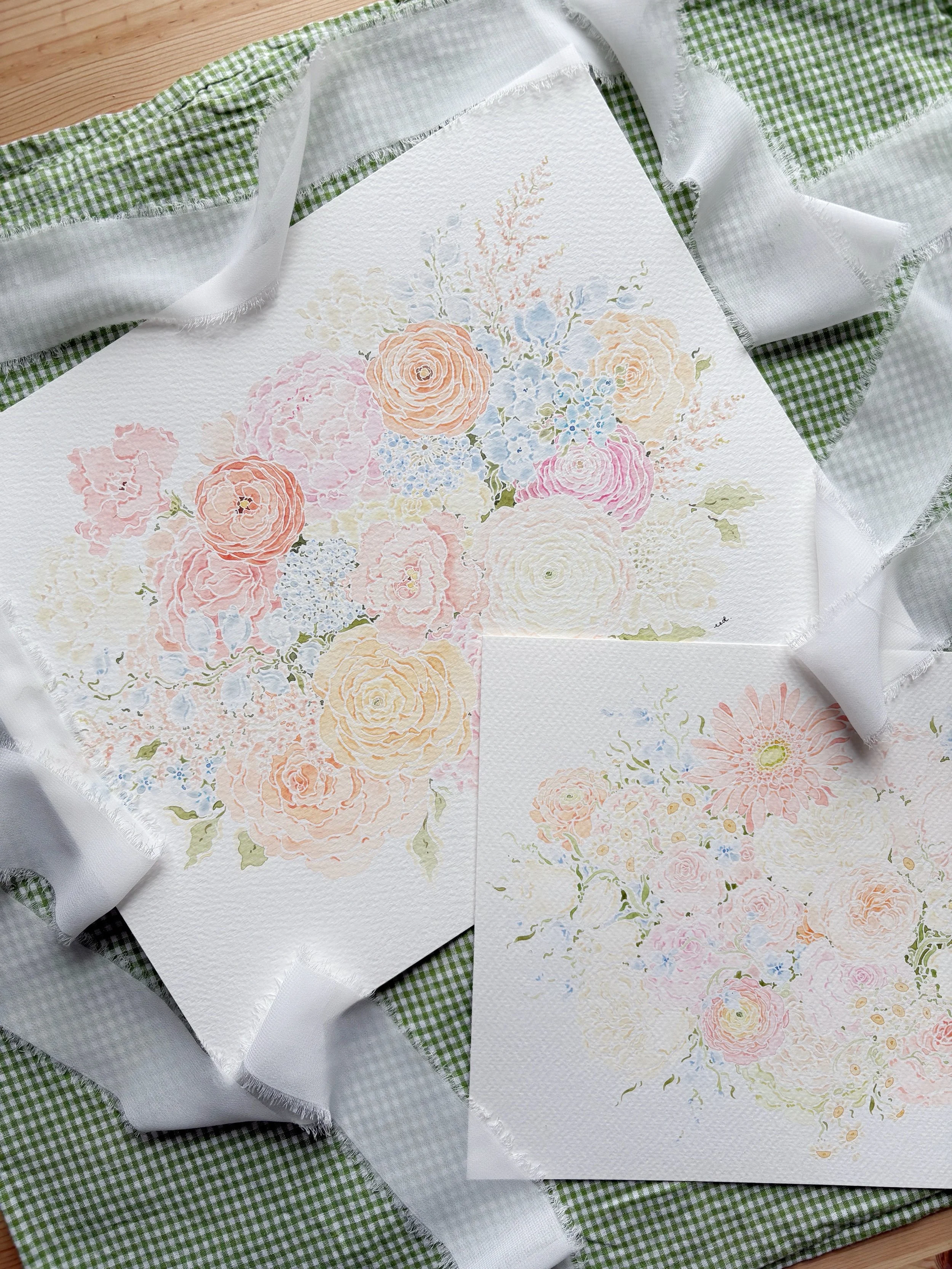 Two watercolor flower illustrations on textured white paper, surrounded by white and green checkered fabric and a light grey ribbon.