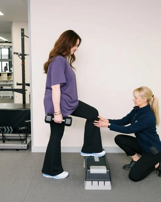 Physiotherapist supporting client with exercises after hip or knee replacement surgery