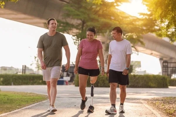 Three young friends walking outdoors in the park at sunset, smiling and enjoying social interaction, reflecting Potentiate Rehab’s focus on mobility and community participation.