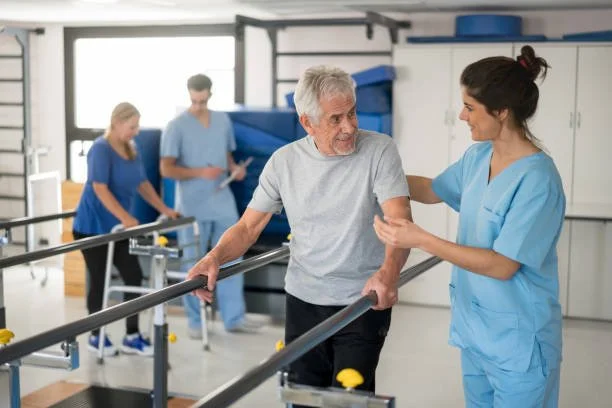 Senior man practicing walking with parallel bars during an NDIS physiotherapy session, guided by a Potentiate Rehab therapist in Sydney.