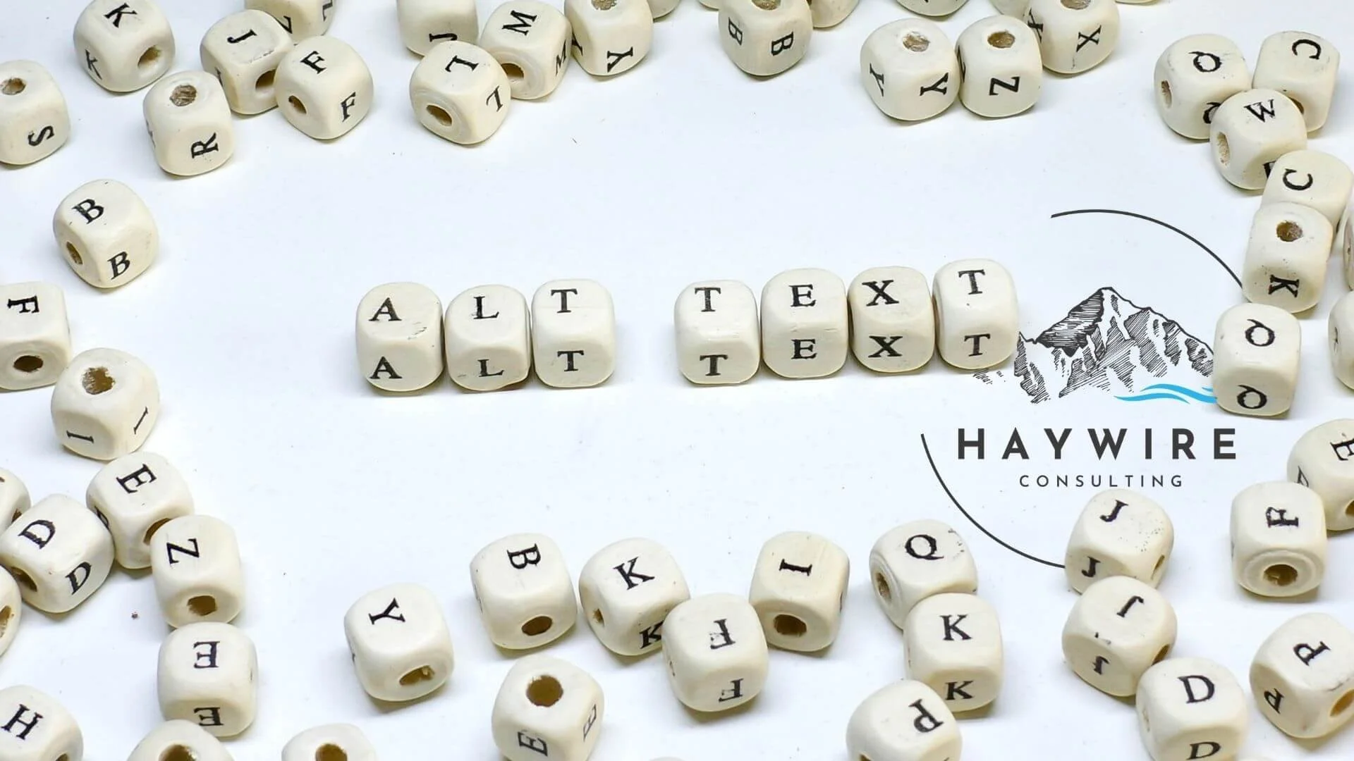 Wooden letter beads spelling out alt text surrounded by a scattering of other letter blocks and the Haywire Consulting logo.