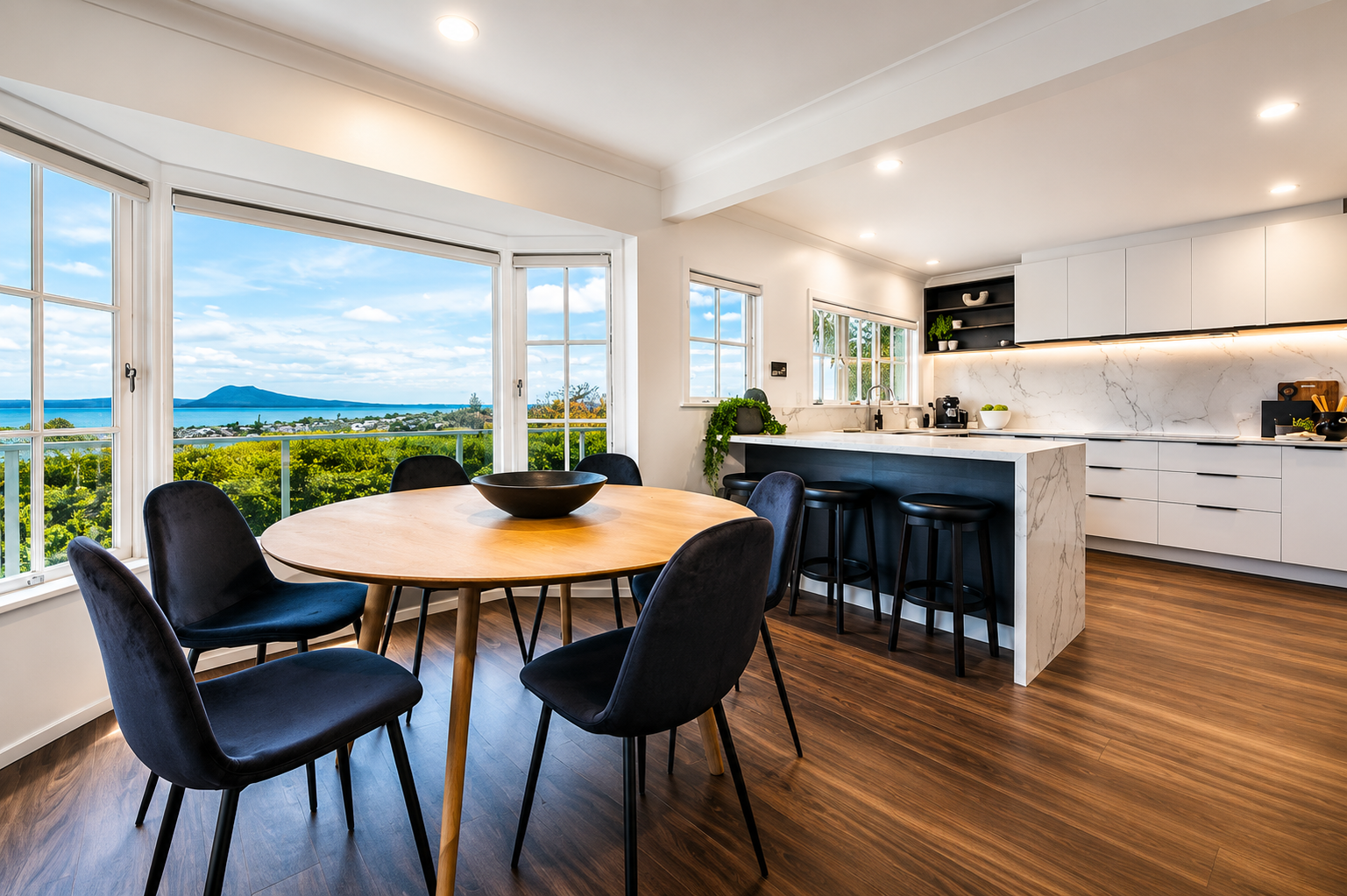 Castor Bay kitchen renovation by Parris Builds featuring an open-plan dining area, stone island and sea views.