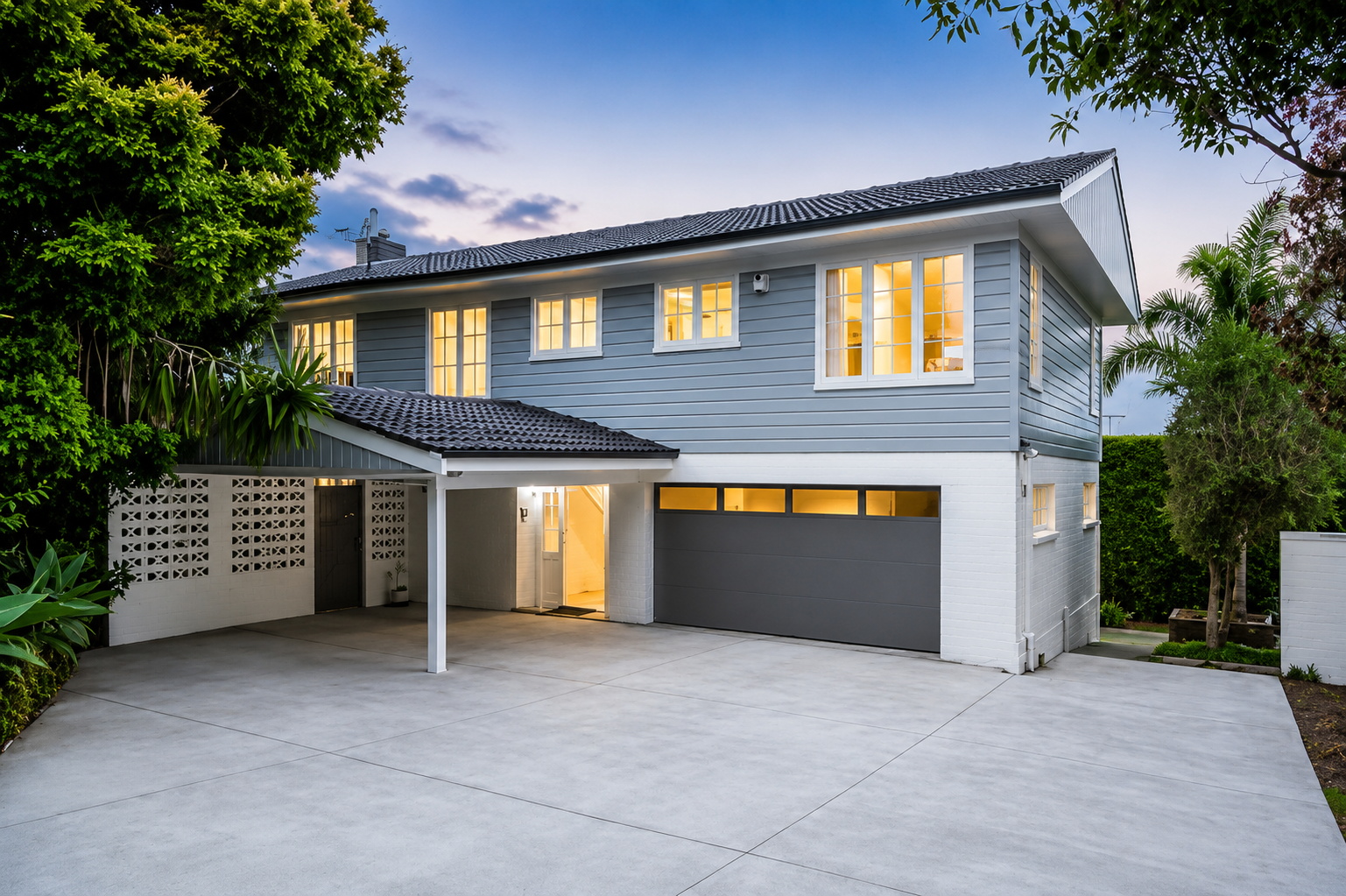 Exterior view of a renovated two-storey home completed by Parris Builds, featuring weatherboard cladding, new driveway and modern garage in Auckland.