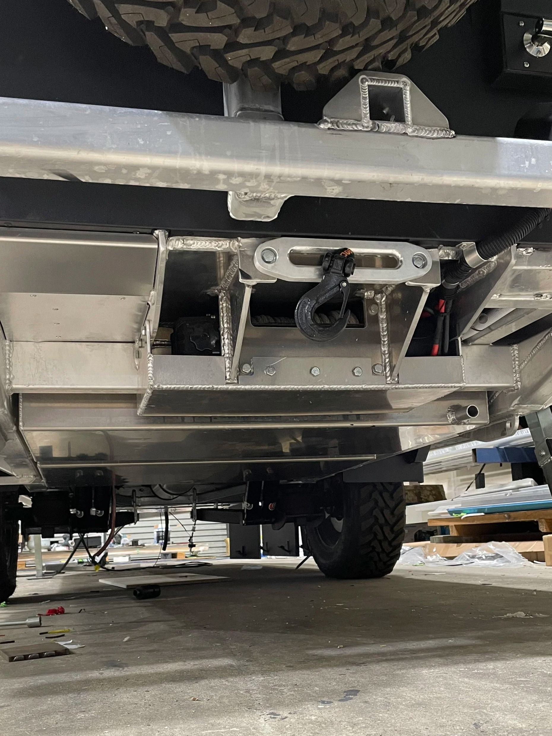 View of aluminium chassis under a caravan with aluminium tanks and a custom rear mounted winch.