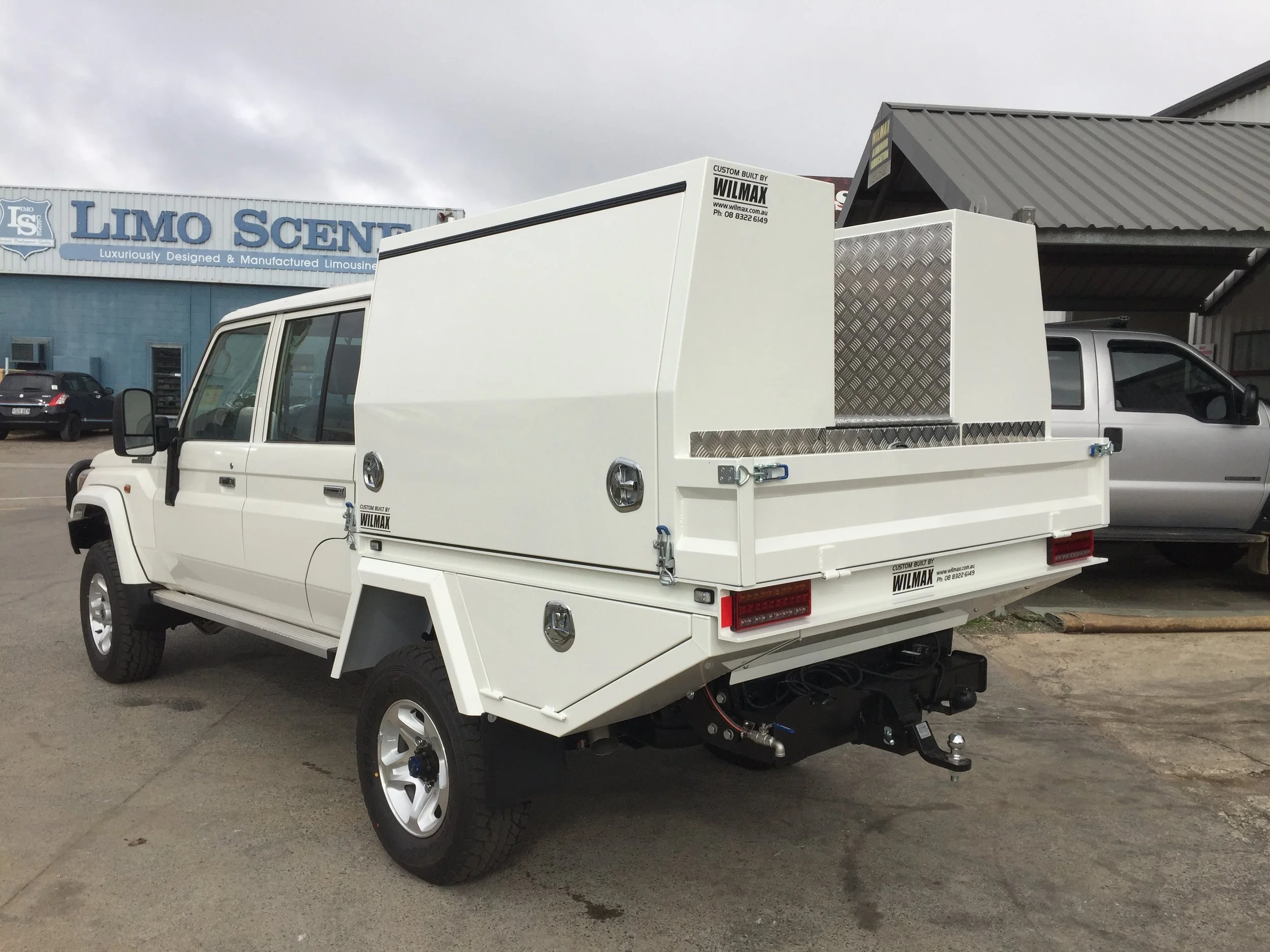 A white utility truck with a specialized box on the back, custom canopy, service body