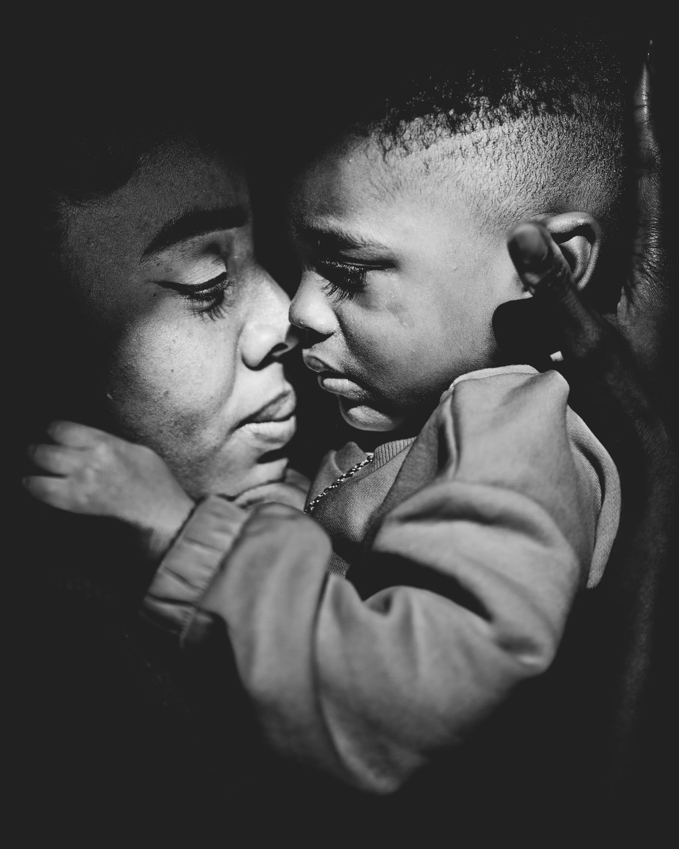 Black and white close-up photo of two children touching foreheads and looking into each other's eyes, demonstrating intimacy and connection.