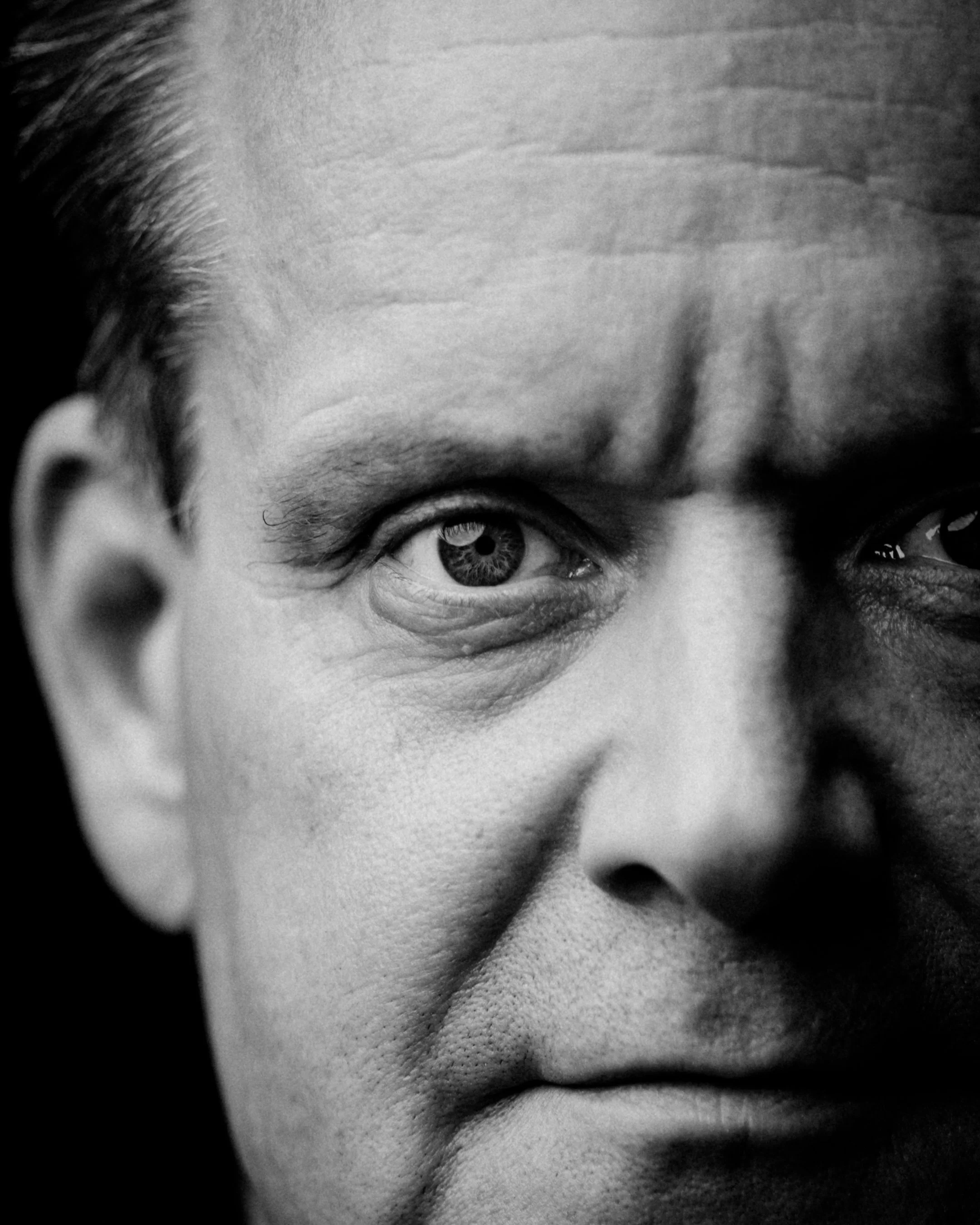 Close-up black and white photograph of a man's face, focusing on his left eye and surrounding features.