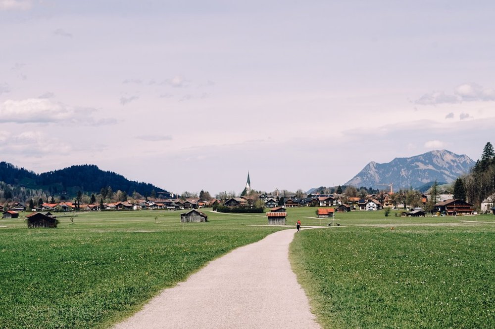Blick auf einen Wanderweg, satte grüne Wiese und Oberstdorf im Hintergrund