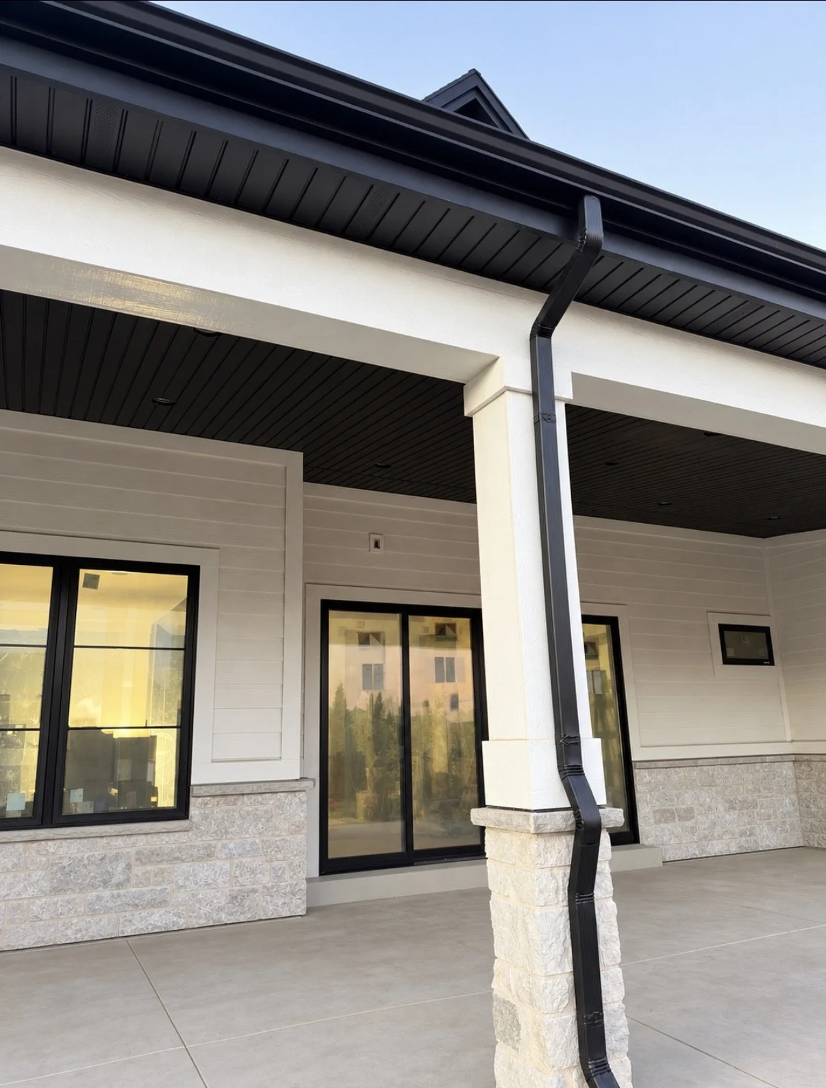 White soffit and fascia installation along a covered exterior walkway with dark gutters.
