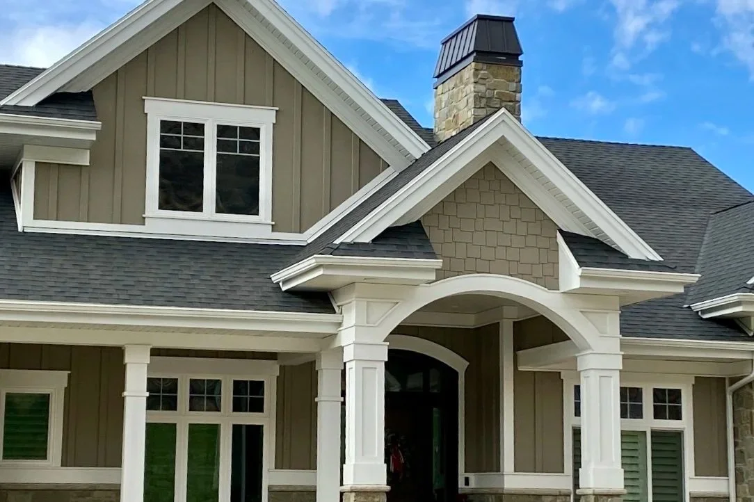 Light gray board and batten siding with white trim and decorative gable accents on a two-story home.