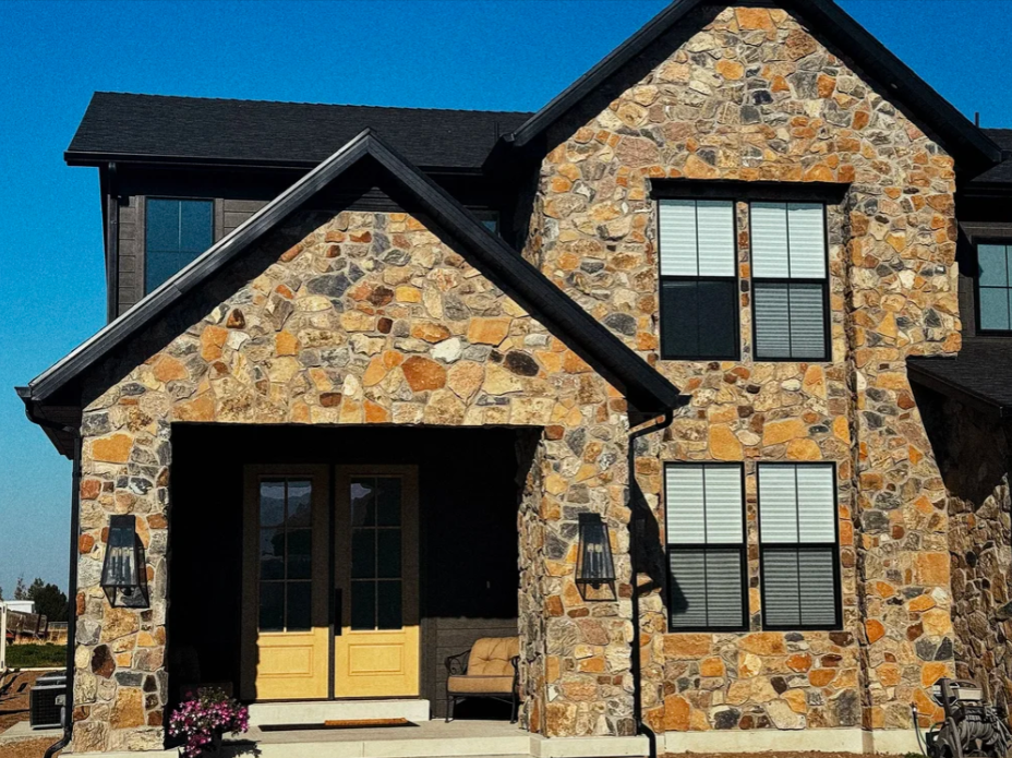 Natural stone veneer surrounding the front entrance of a two-story home with a covered entry