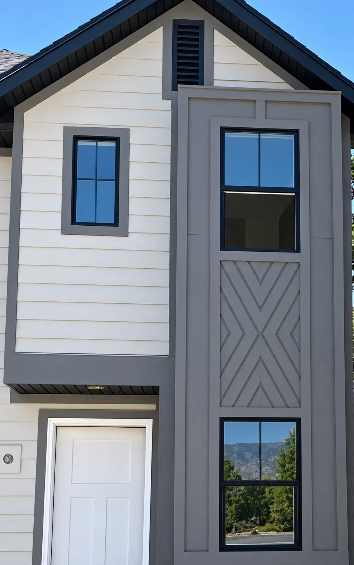 Light-colored painted exterior siding with decorative board-and-batten detailing, dark windows, and gable trim.