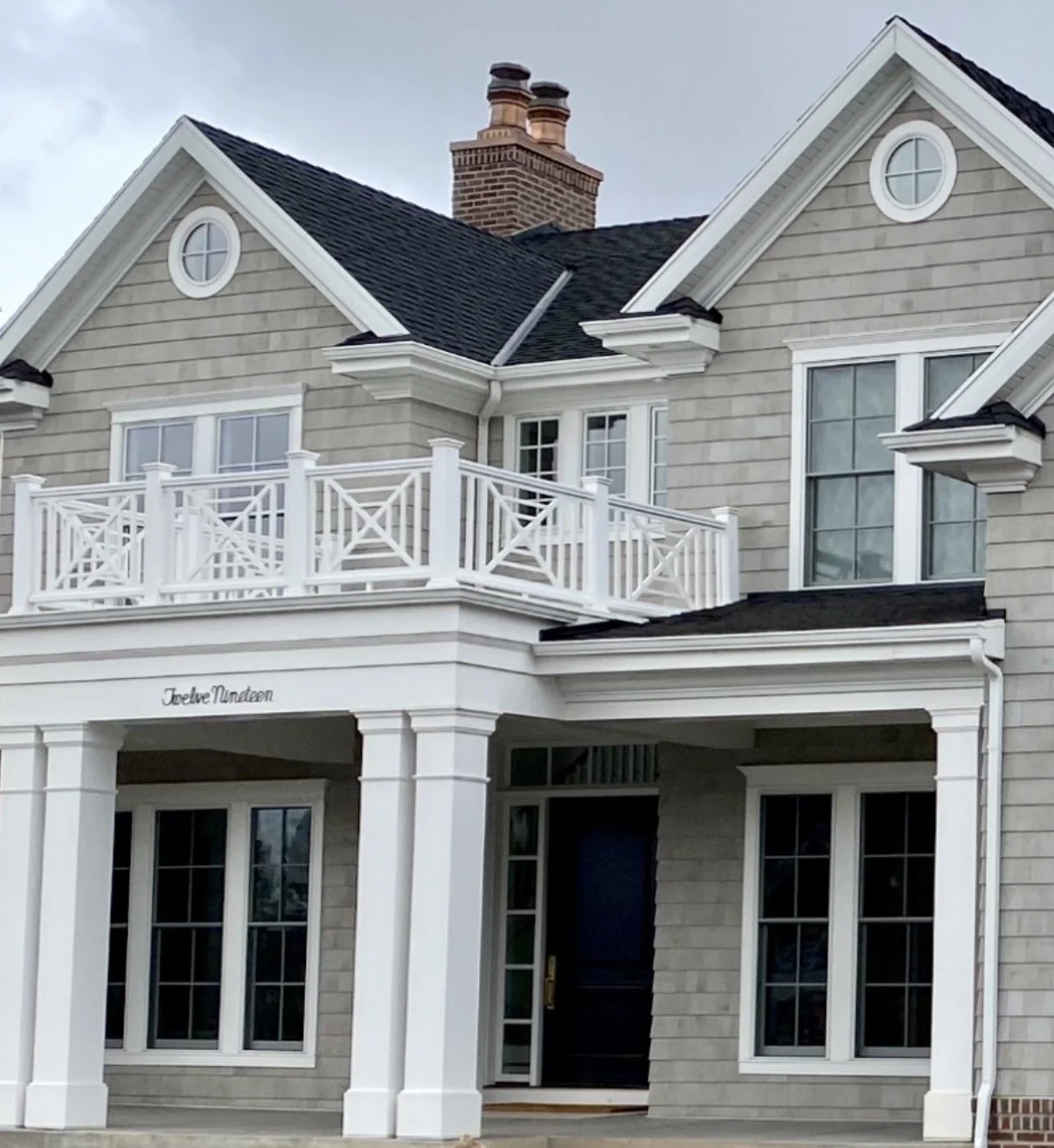 Coastal-style home featuring white decorative exterior trim, detailed porch columns, custom balcony railings, and window surrounds.