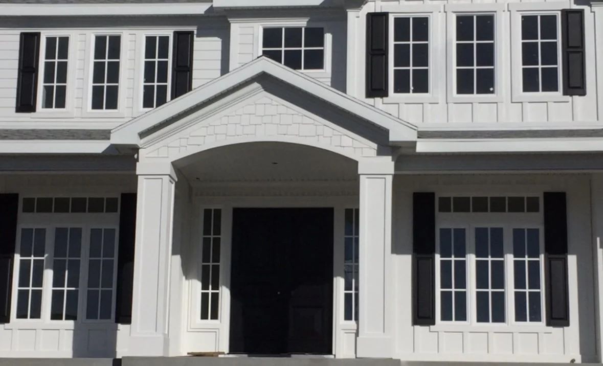 Modern farmhouse exterior with board-and-batten siding, shake accents, custom window trim, porch details, soffit, and fascia.