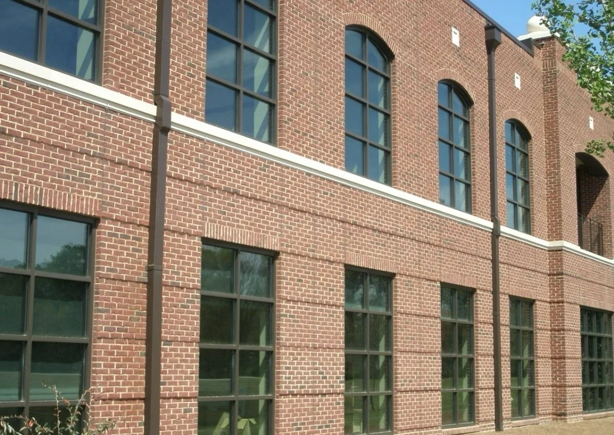 Traditional red brick masonry on a multi-story commercial building with tall windows