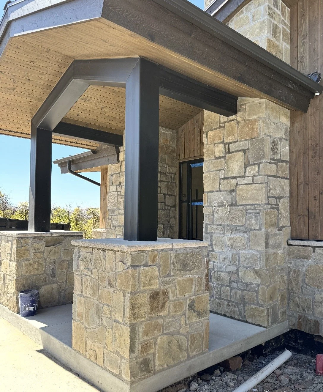 Full-bed natural stone masonry on exterior porch walls and columns beneath a covered roof
