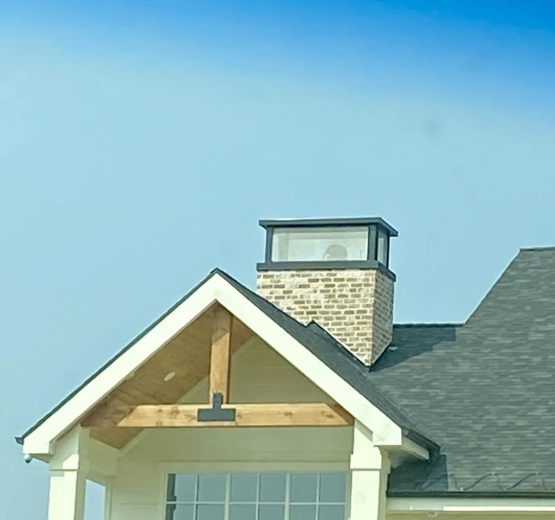 Custom exposed timber gable accent above a covered entry with white trim and stone chimney