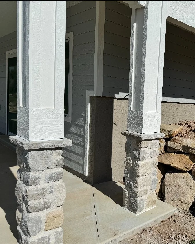 Close-up of custom white column wraps with stone bases and exterior trim