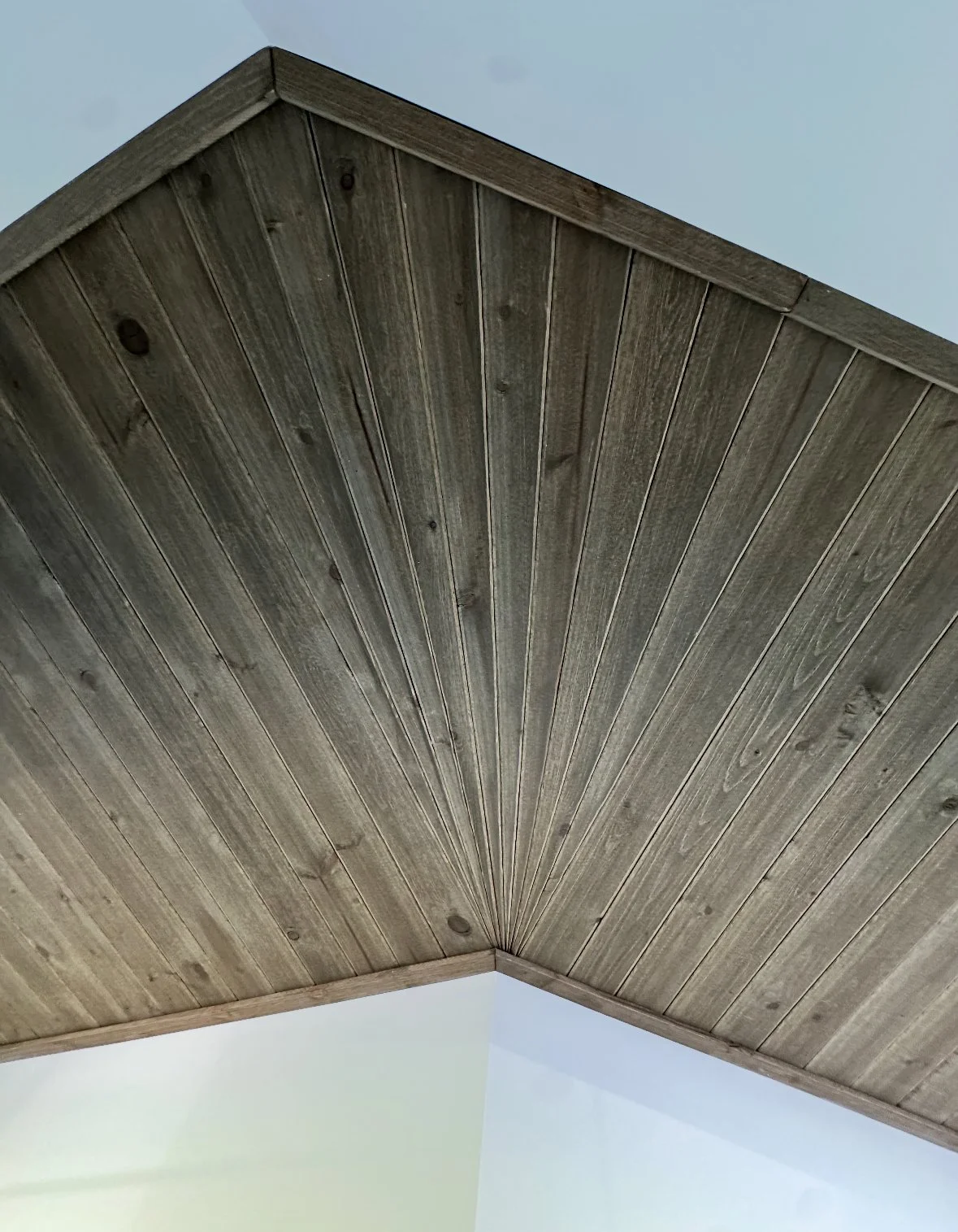 Stained cedar ceiling installed around a corner in a hallway