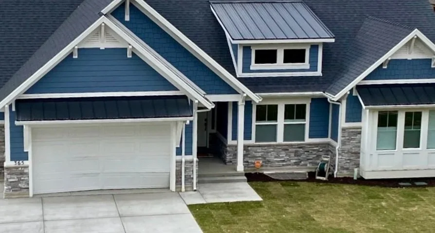 Custom metal roof overbuild above a garage opening on a home with decorative gables and contrasting exterior trim.