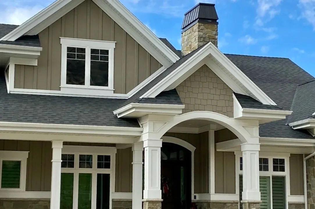 Two-story home with light-colored painted siding, white exterior trim, and decorative front entry columns.