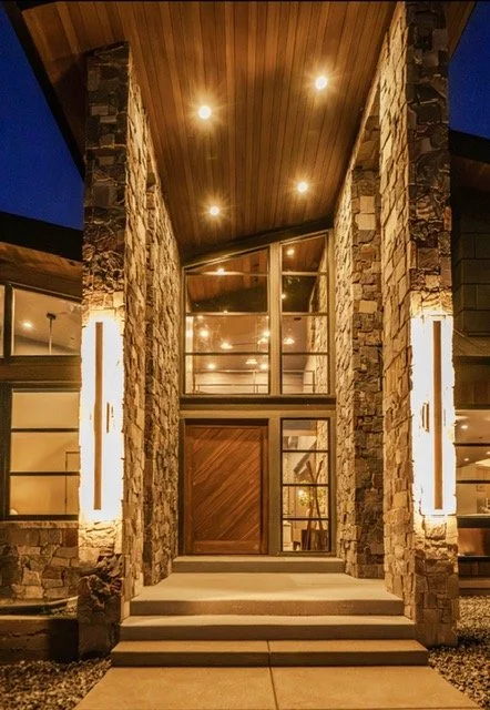 Warm stained cedar ceiling with recessed lighting above a covered outdoor kitchen and stone columns