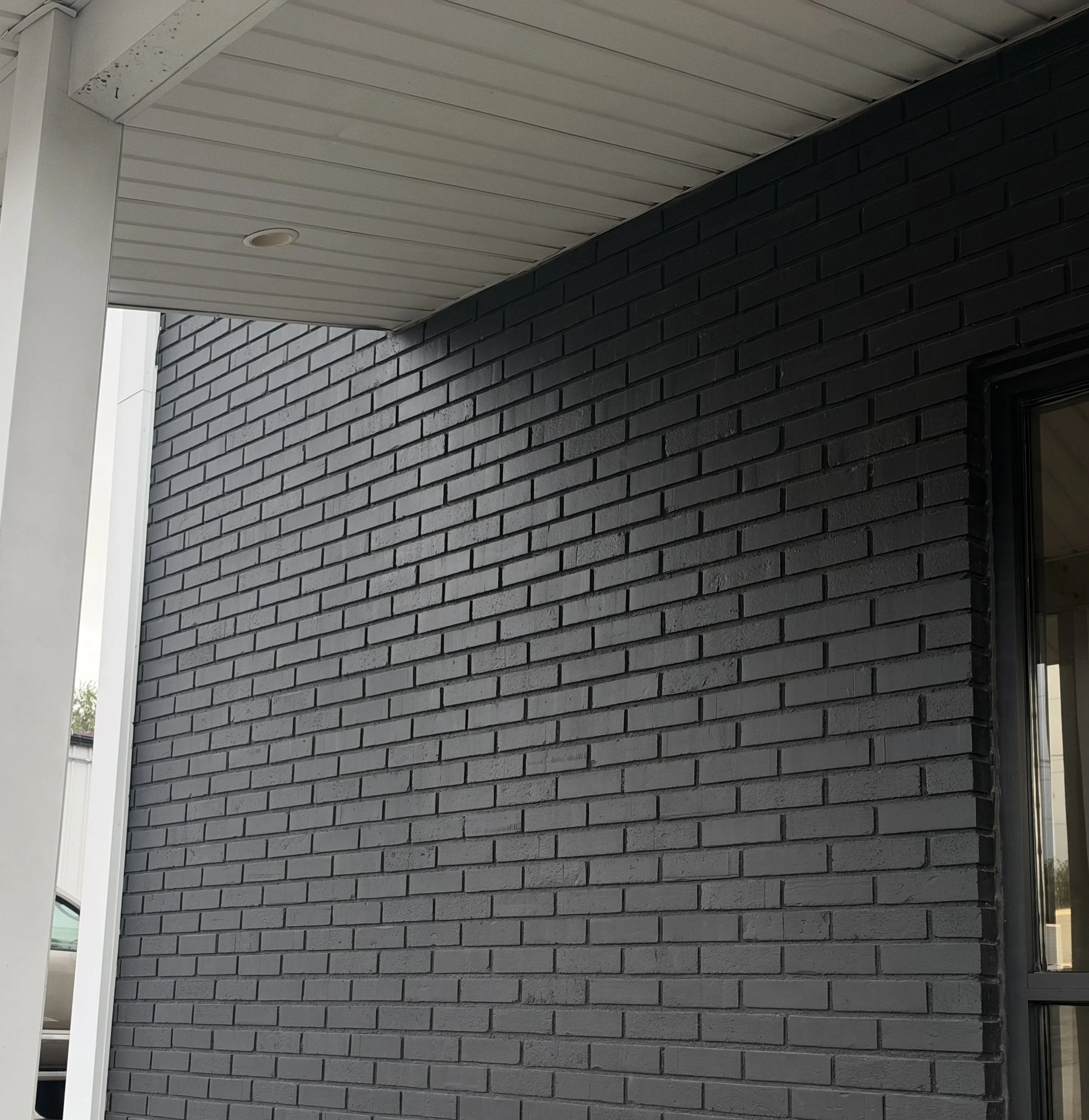 Light gray brick masonry wall beneath a white covered porch ceiling