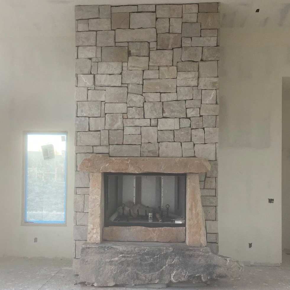 Floor-to-ceiling interior stone fireplace featuring light-colored rectangular stone and a recessed firebox.