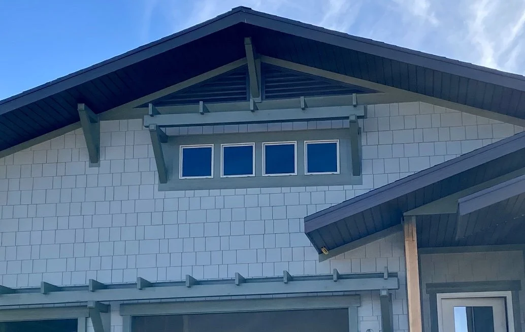 Custom decorative corbels beneath the roofline of a home with blue-gray siding