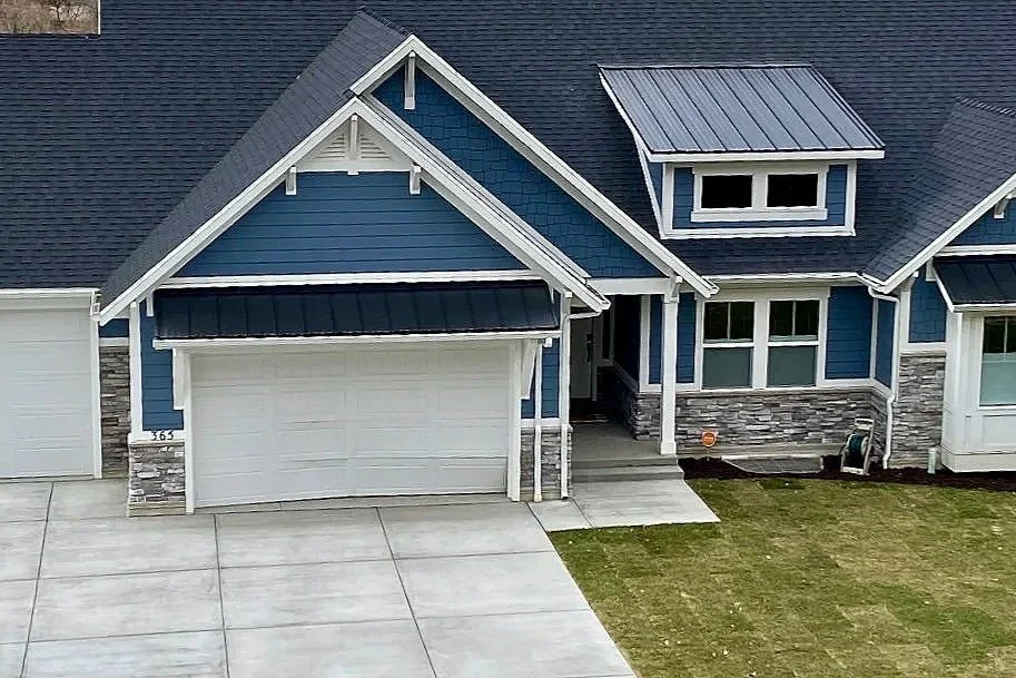 Dark painted exterior siding with contrasting white trim on a home featuring multiple gables and an attached garage.