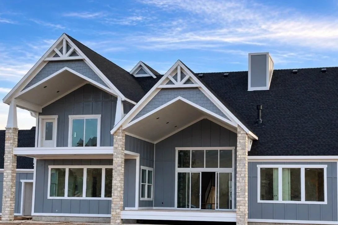 Large two-story home with painted gray-blue siding, white trim, and decorative gable accents.