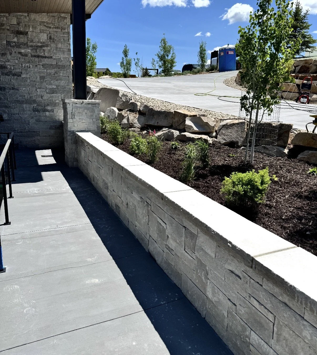 Full-bed stone retaining wall bordering a landscaped garden and concrete walkway