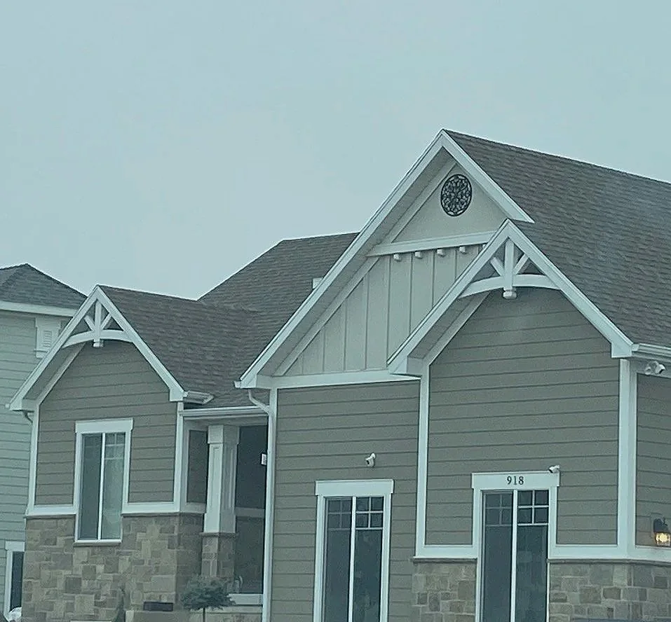 Gray horizontal lap siding on a home with white decorative gable trim and stone masonry accents.