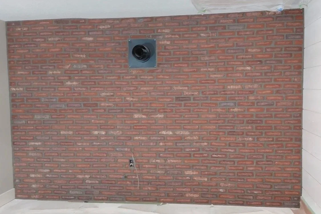 Interior brick masonry accent wall featuring a warm red and brown brick finish.
