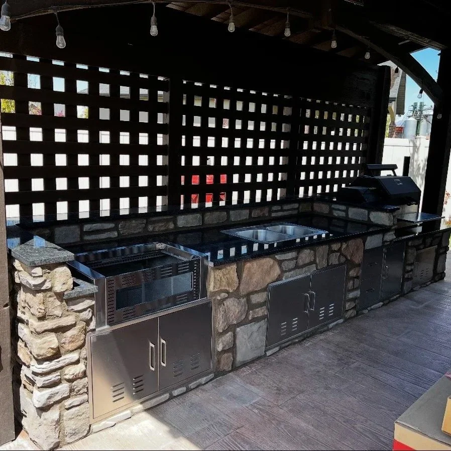 Custom outdoor stone masonry counter and seating area beneath a covered wooden structure with decorative lattice panels.