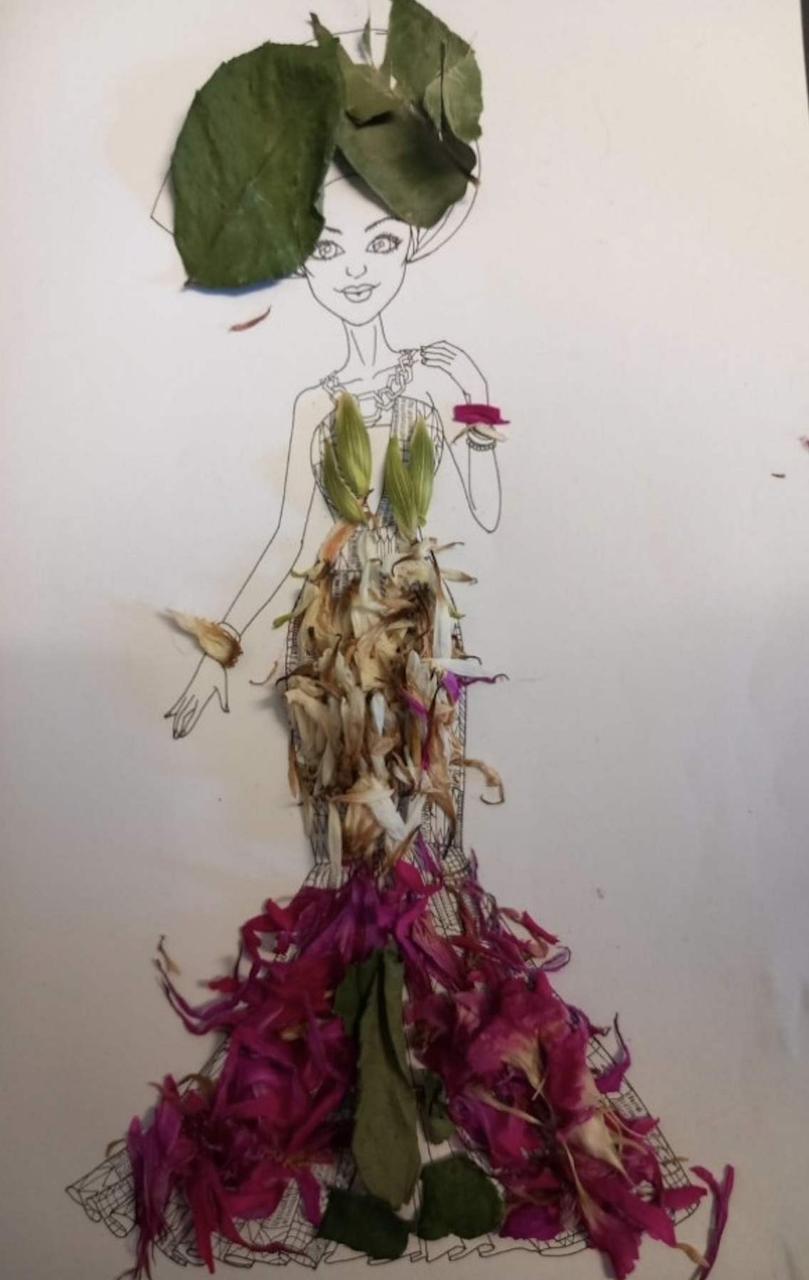 A drawing of a woman wearing a dress made of various flower petals and leaves. The drawing is on a white background, and real leaves and flower petals are arranged on the drawing to create the dress and accessories.