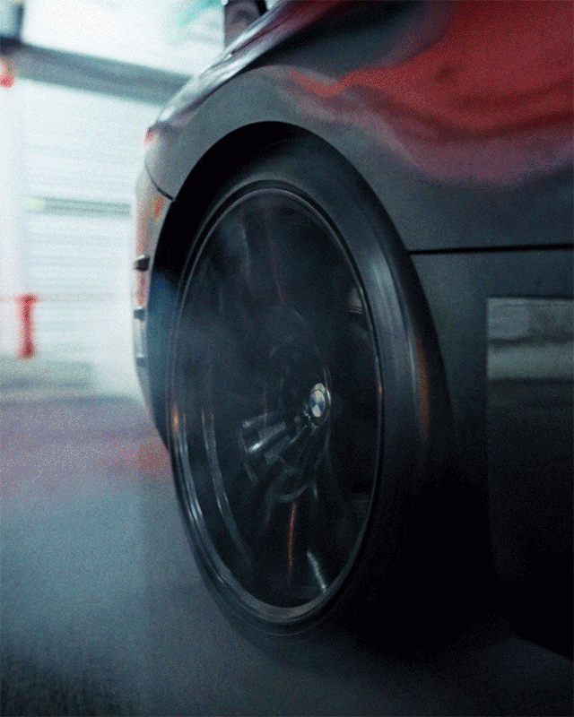 Close-up of a black car wheel in motion on a road.