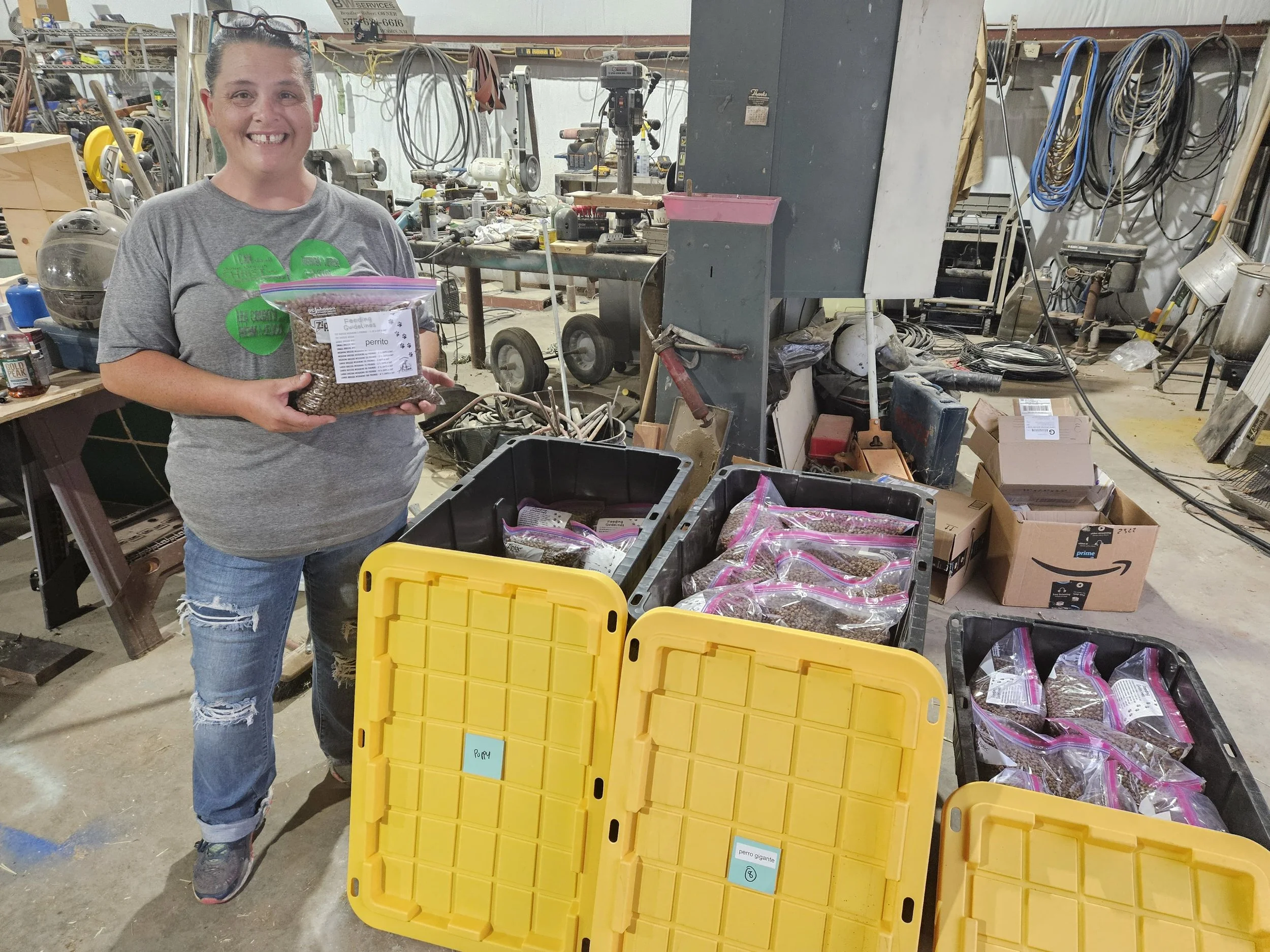Person holding a bag of pellets in a workshop with plastic bins and bags.