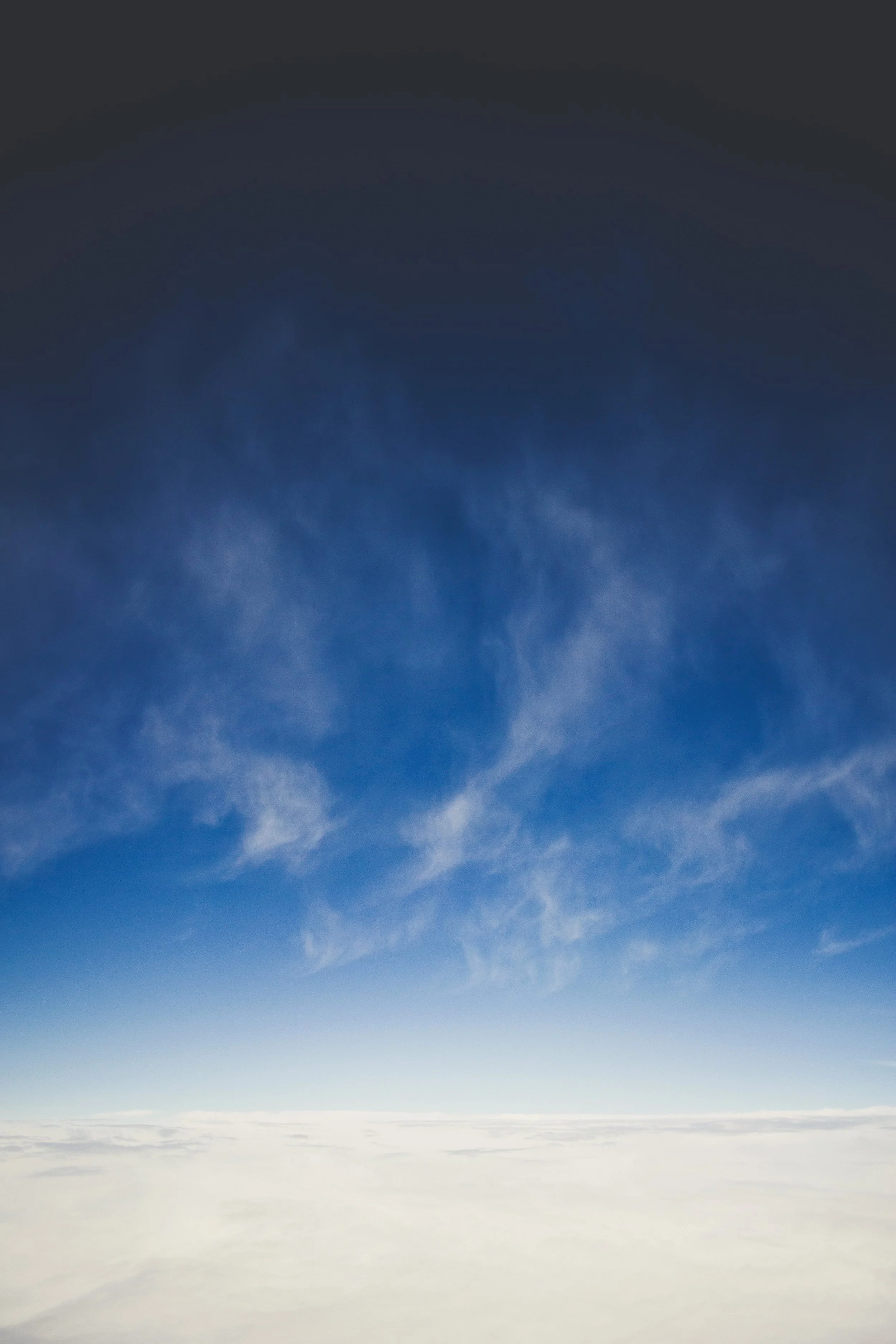 View of the sky above clouds, transitioning from dark blue at the top to light blue near the horizon.