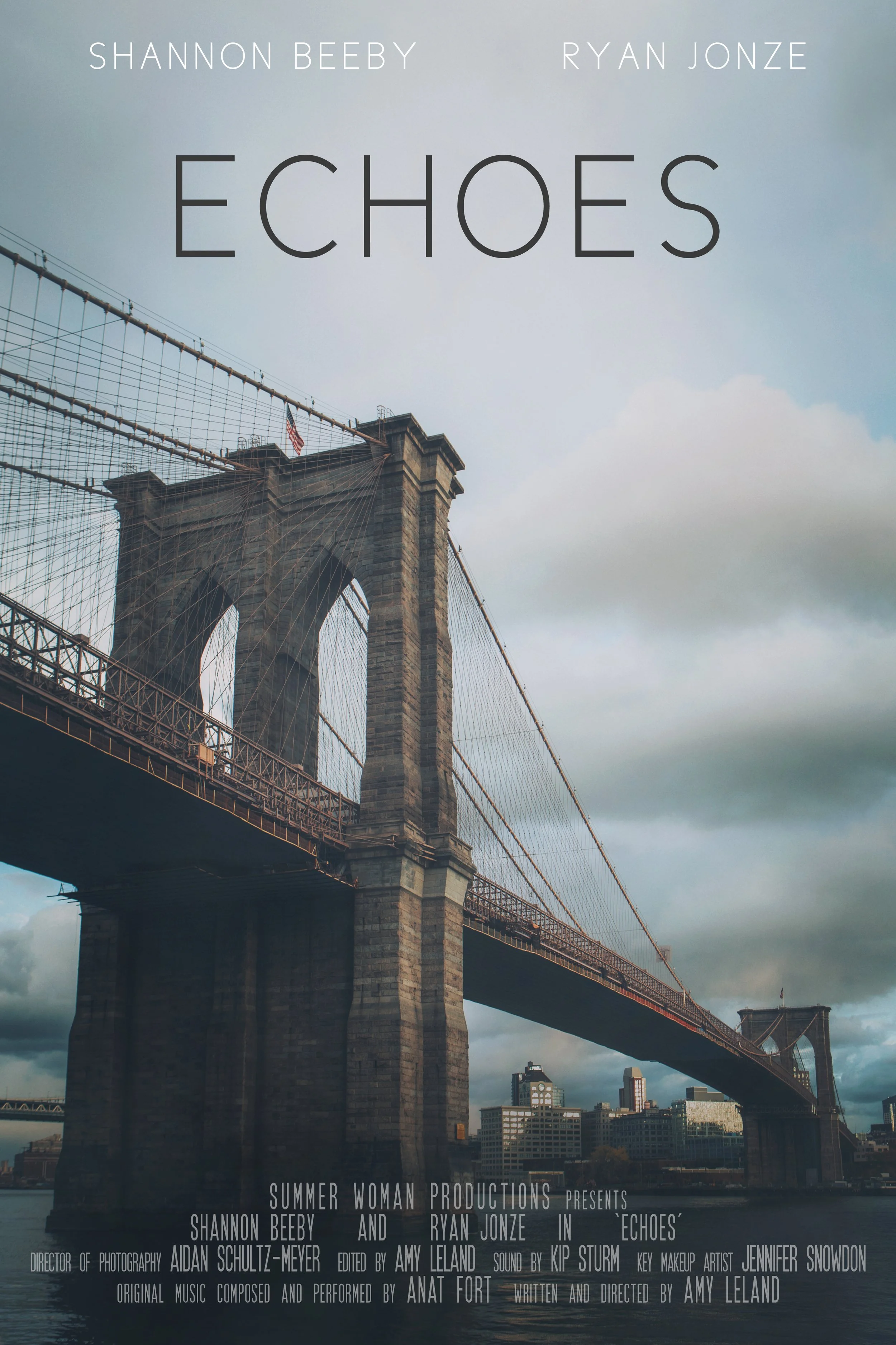 Photograph of the Brooklyn Bridge in New York City with an overcast sky, displaying the bridge's stone towers and suspension cables, with city buildings in the background.