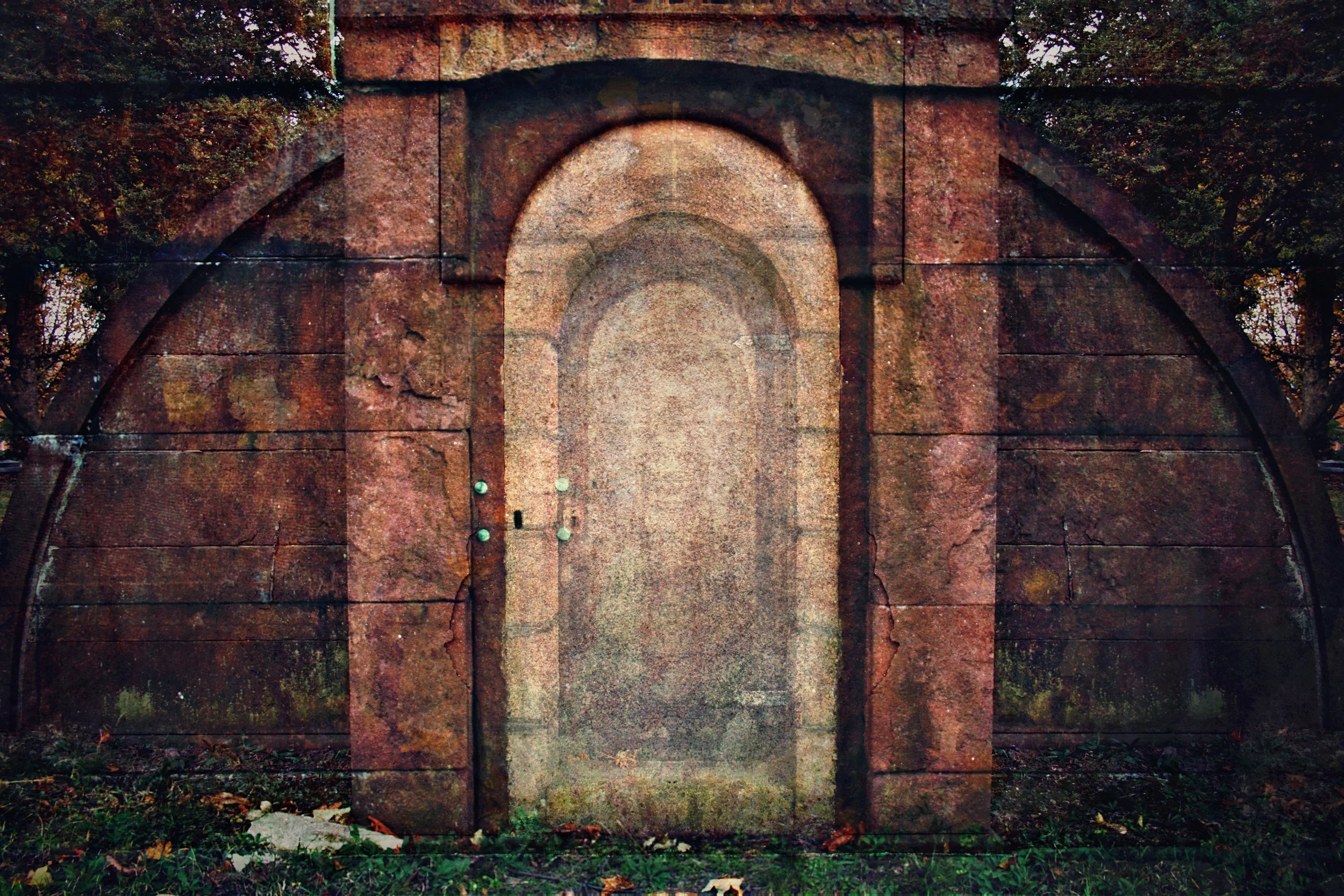A large, old stone wall with an arched opening in the center, surrounded by trees and foliage.