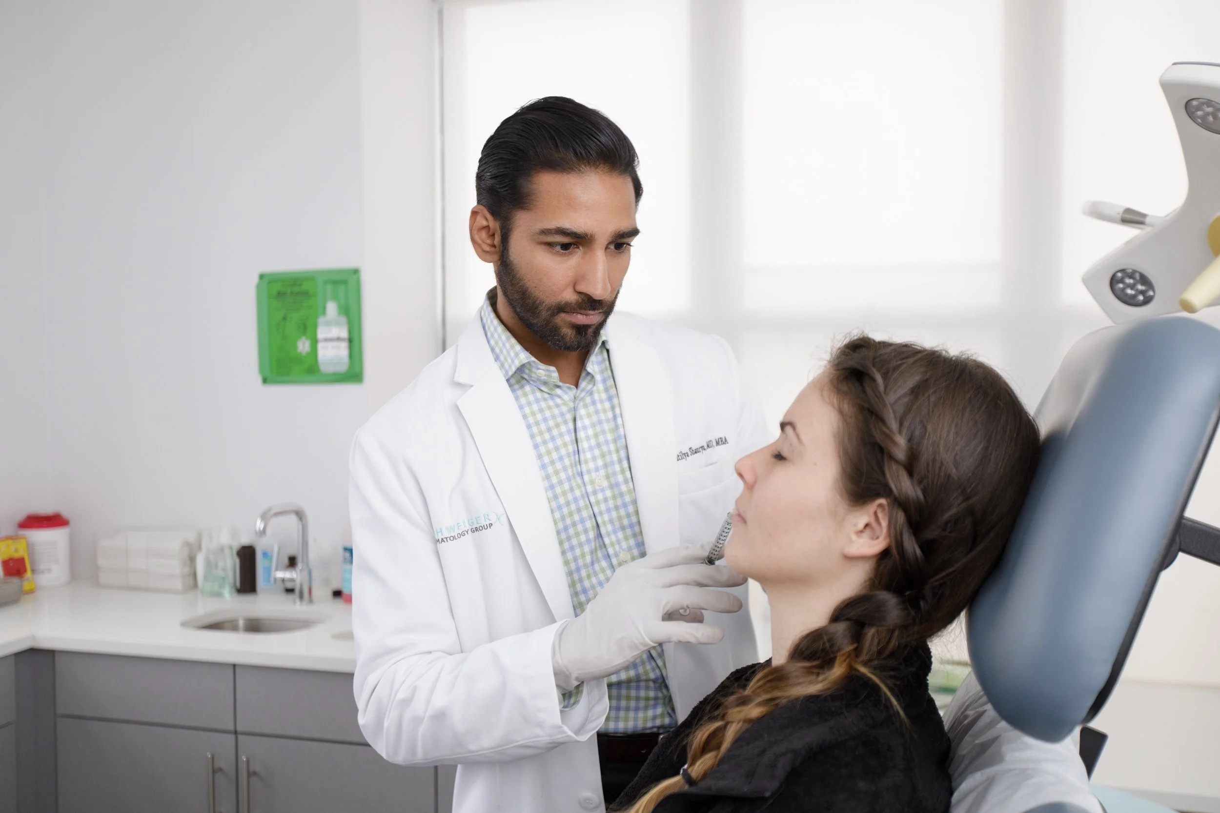 A male doctor examines a female patient's throat in a medical office.