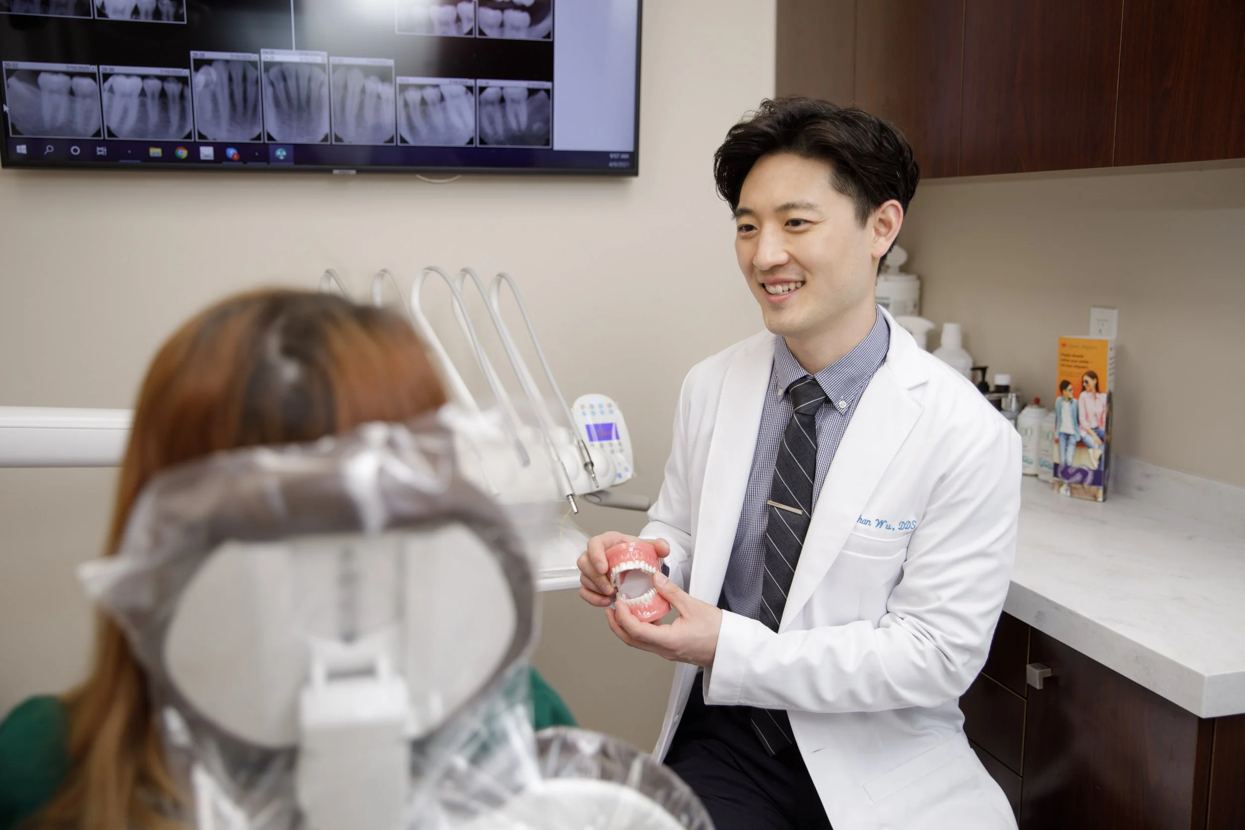 A dentist holding a dental model and explaining it to a patient in a dental office.