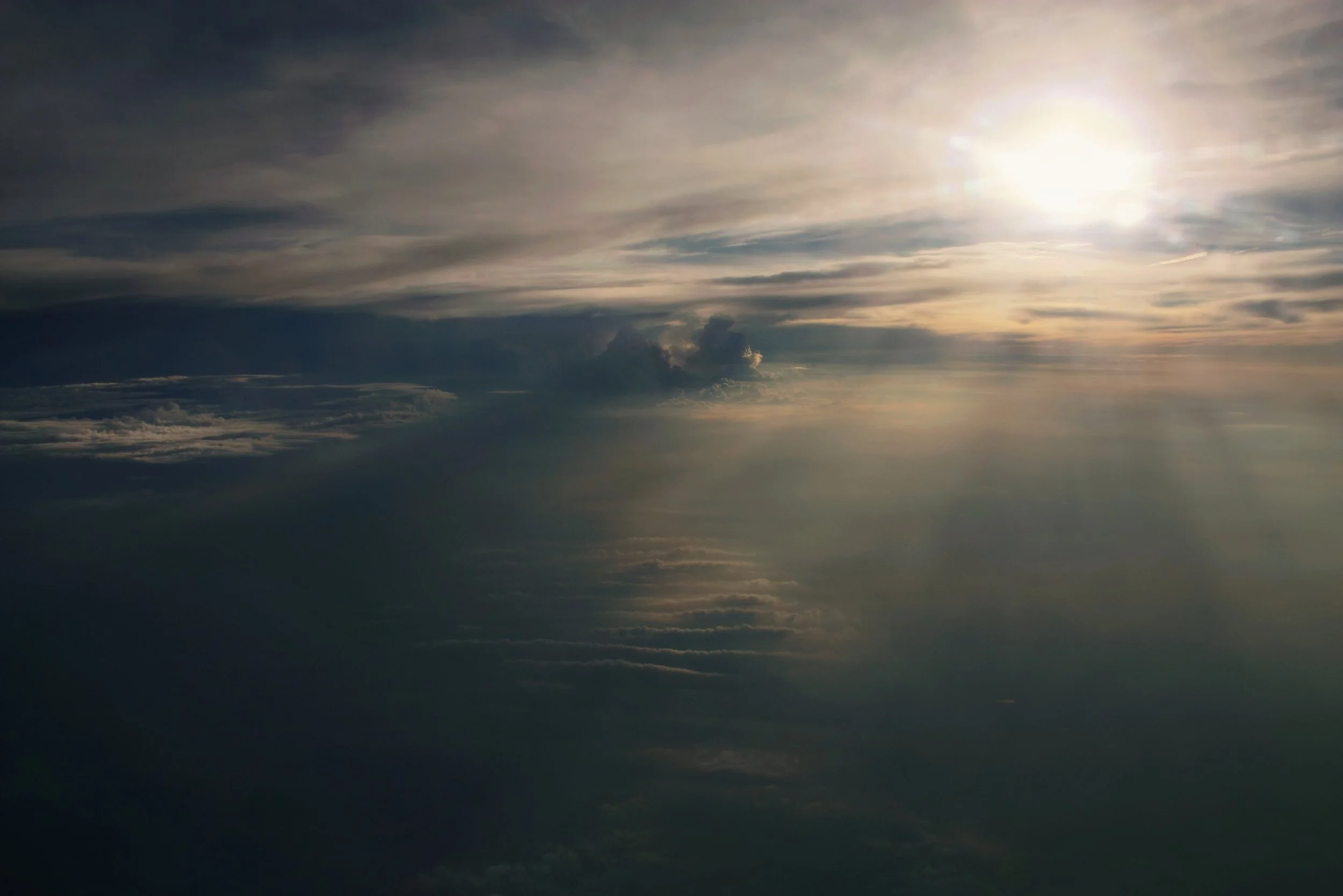 A view of a cloudy sky with the sun shining through, creating a bright glow amid the clouds.