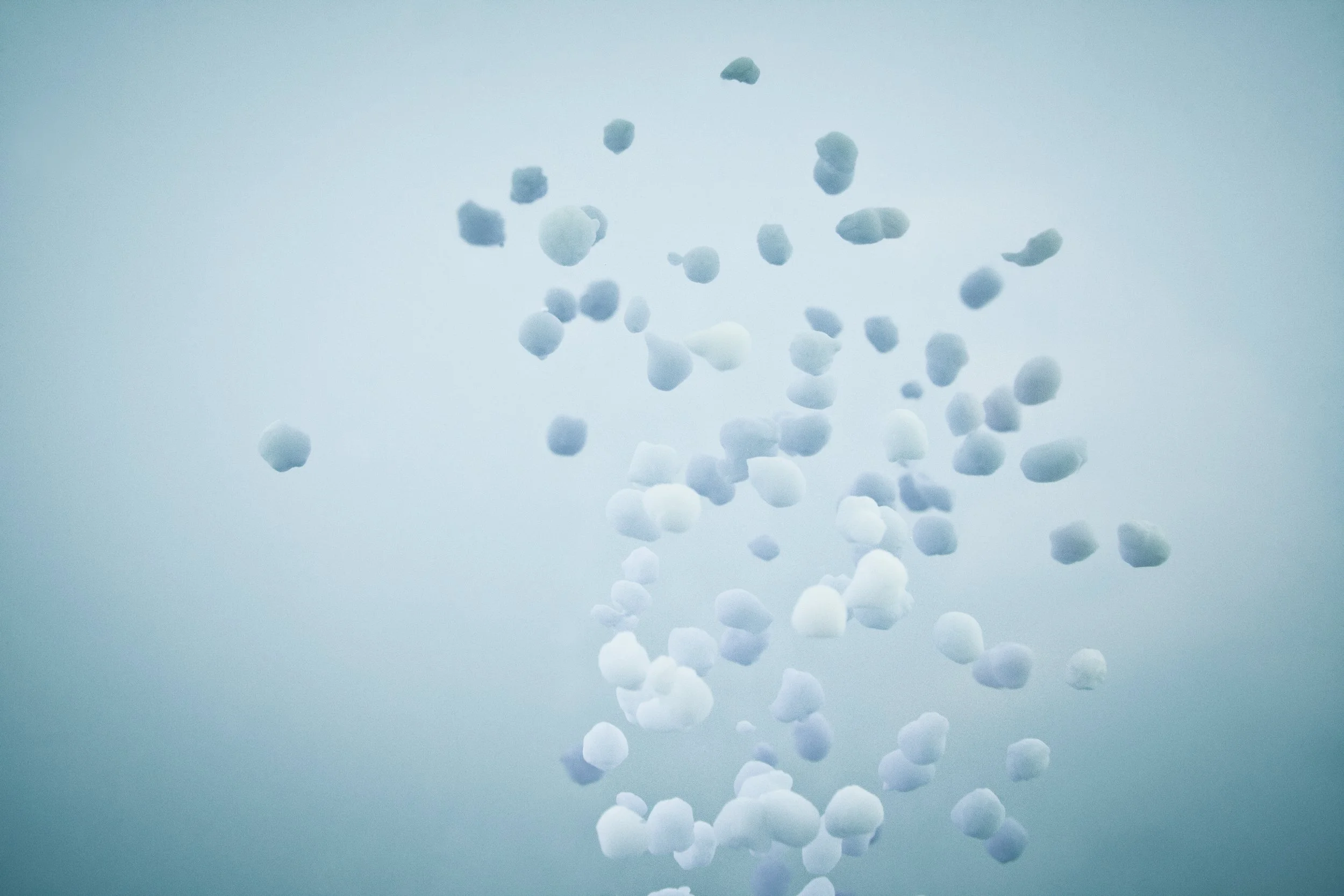 Multiple white pills floating against a clear blue sky background.