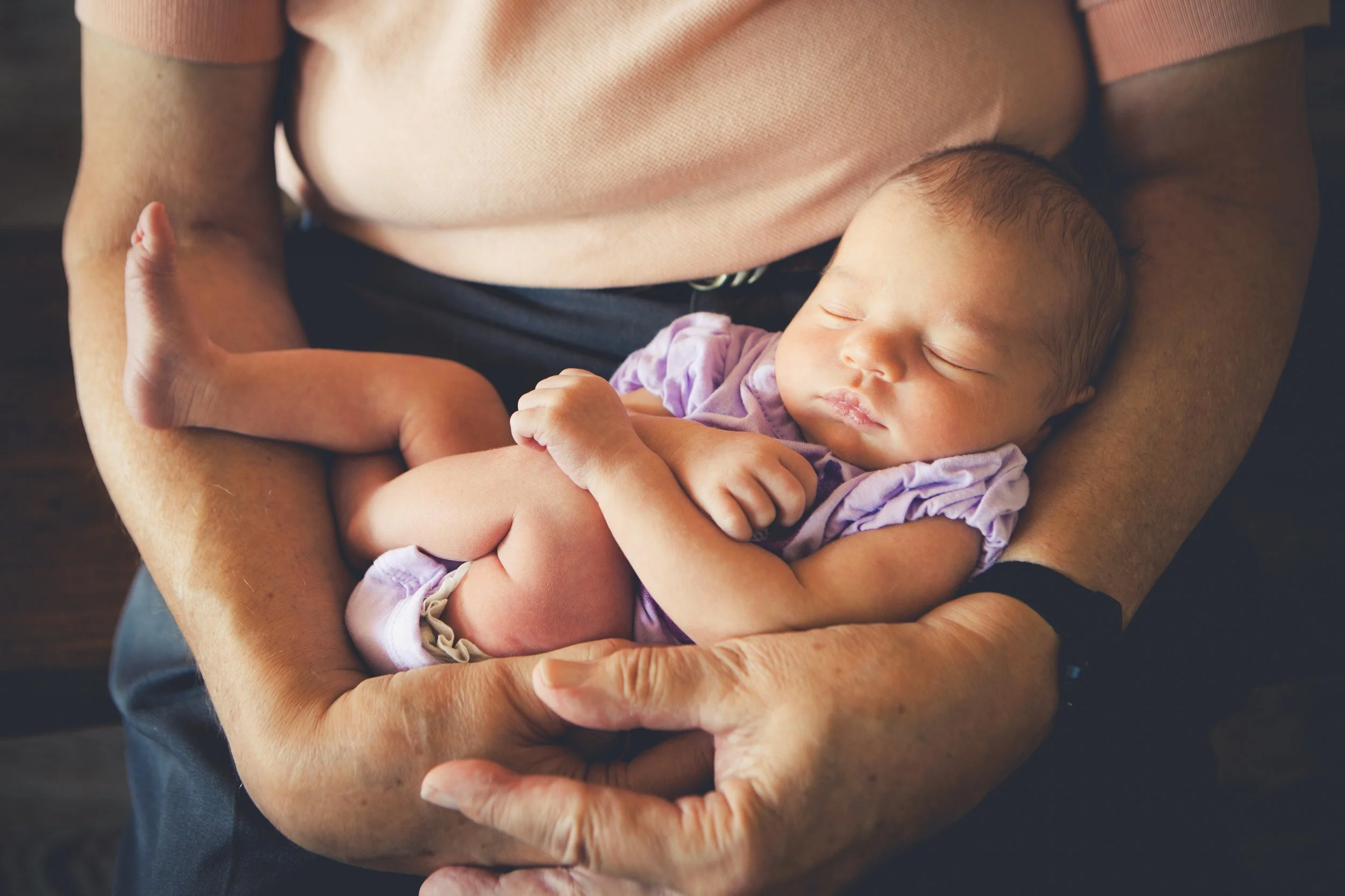 A person holding a sleeping baby in their arms.