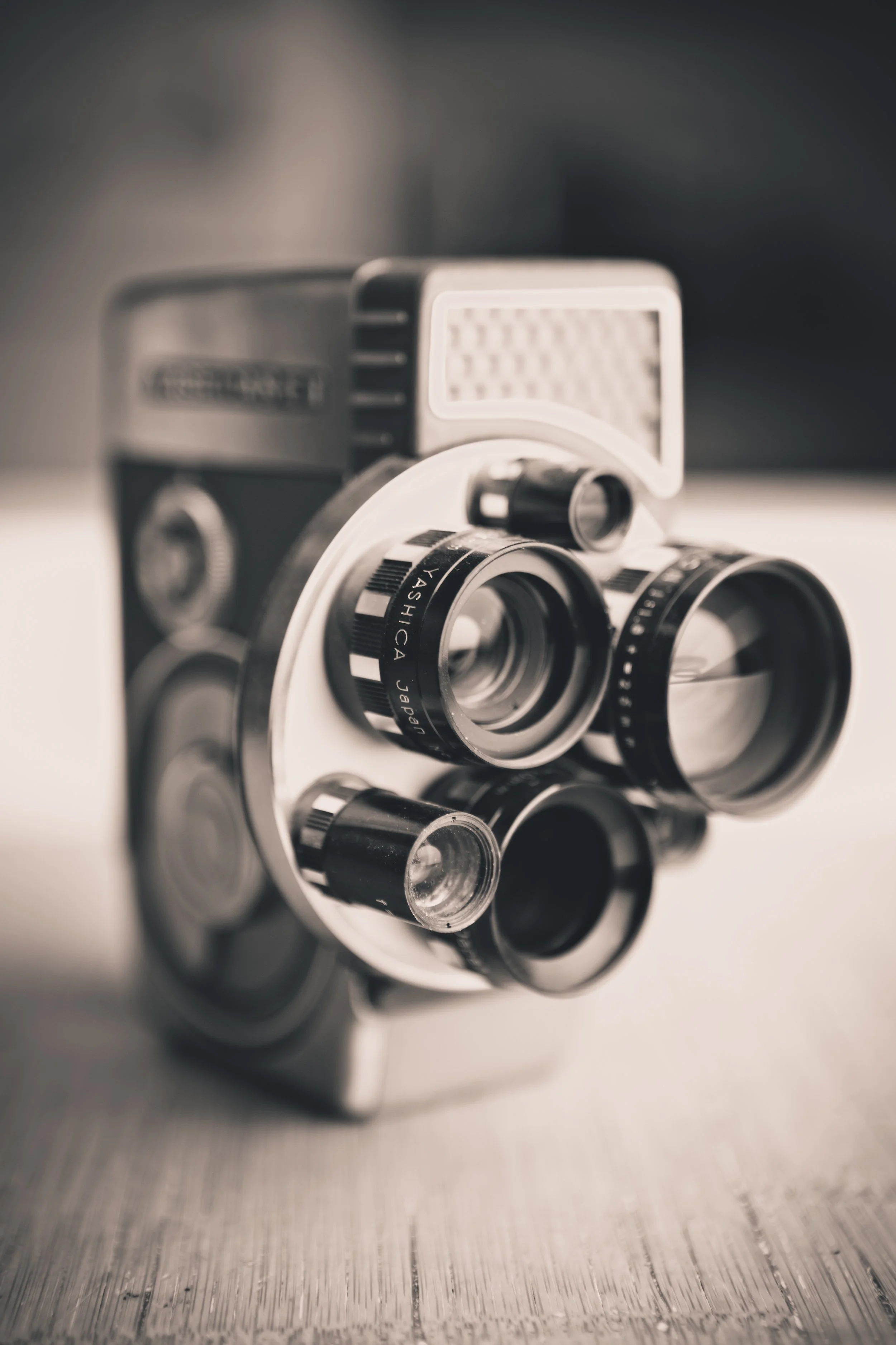 Optometrist's trial lens set with multiple black and silver lenses arranged on a mirror. The lenses have labels with specifications written on them. The set is placed on a textured surface with a blurred background.