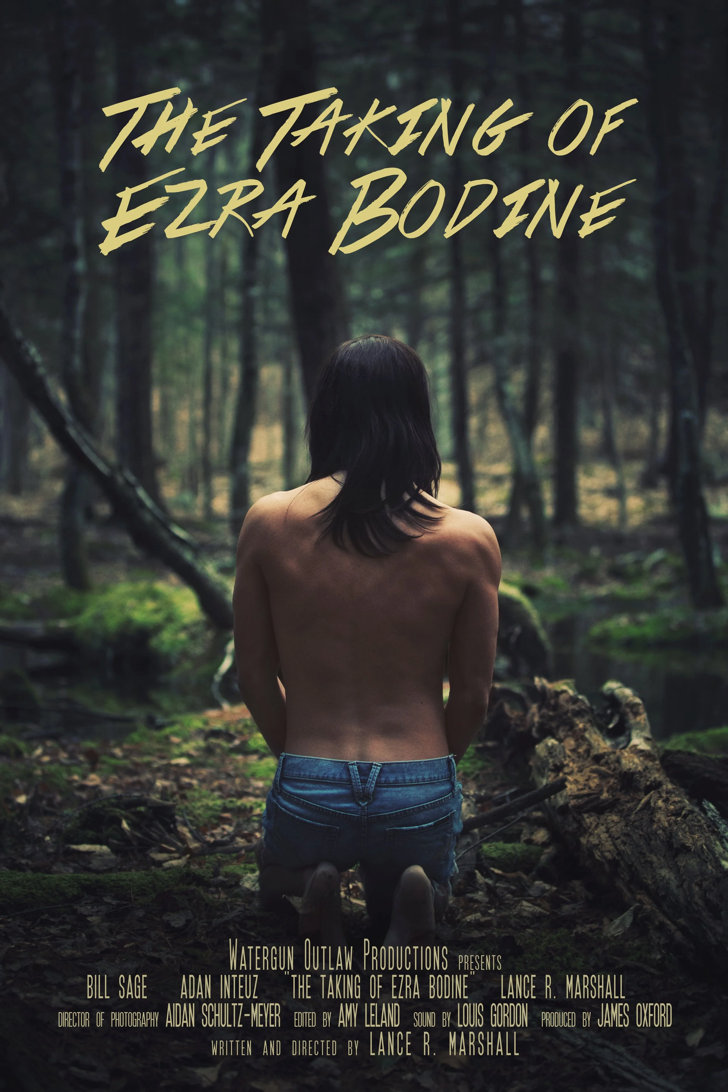 A woman with dark hair, wearing jeans, kneeling in a wooded forest, with windblown trees and a misty atmosphere. The text overlay says, 'The Taking of Ezra Bodine' and credits various production team members.