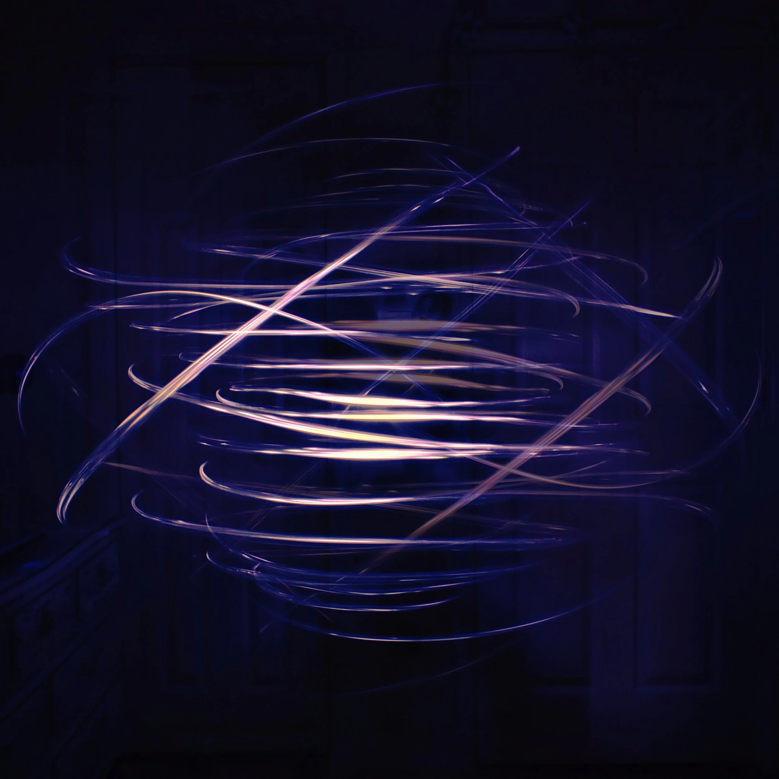 Light trails of purple and white streaks in a dark environment, creating abstract swirling patterns.