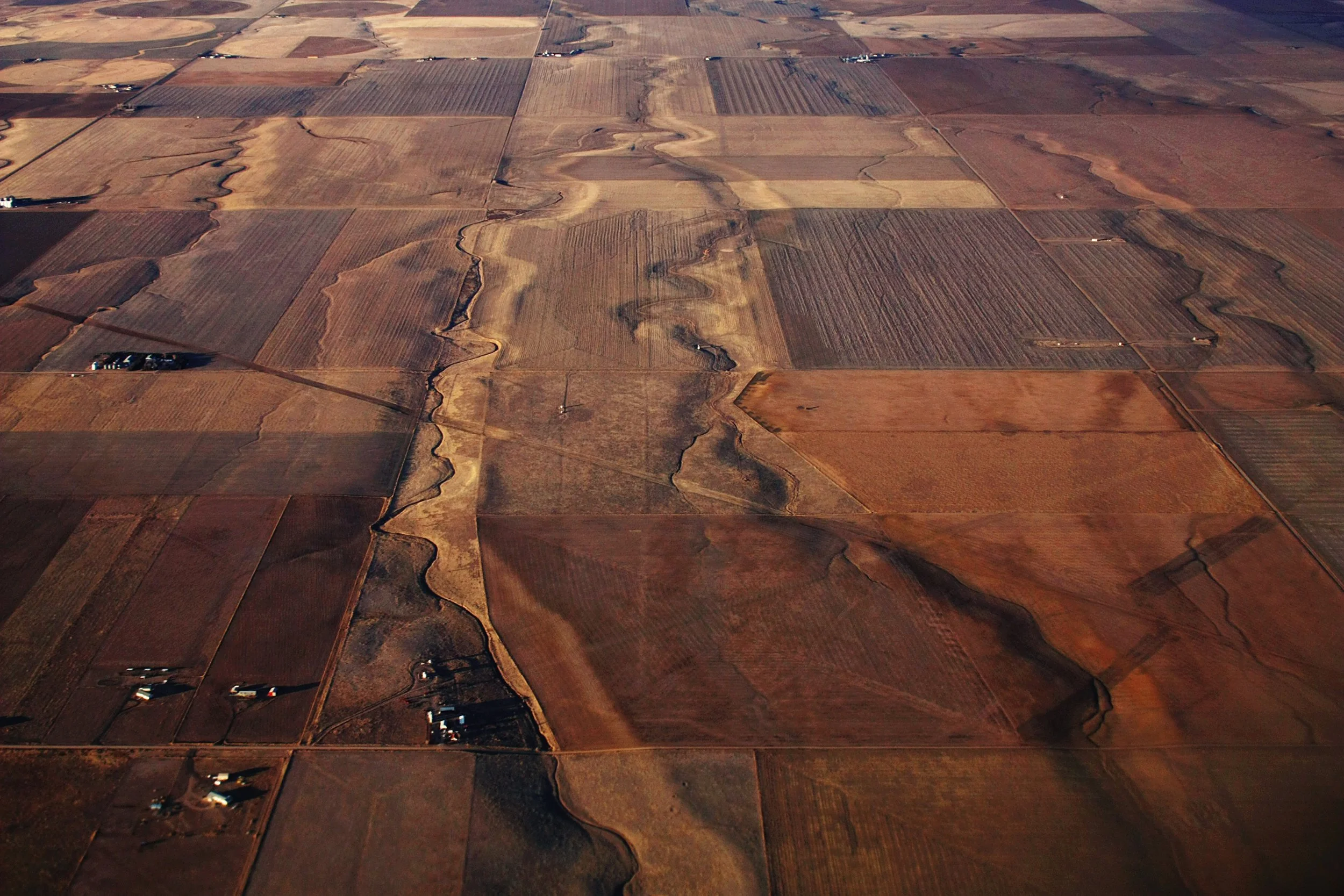 Aerial view of a patchwork of farmland with a winding river running through the fields.